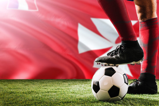 Close up legs of Wallis And Futuna football team player in red socks, shoes on soccer ball at the free kick or penalty spot playing on grass. - Powered by Adobe