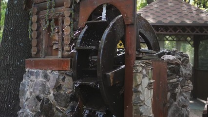 Old wooden decorative water mill on the water vertical