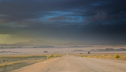 Road in the desert under dark stormy sky
