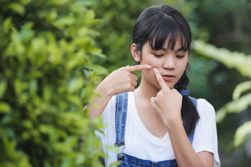 asia teenager young girl hands pressing pimples on skin problem face in garden