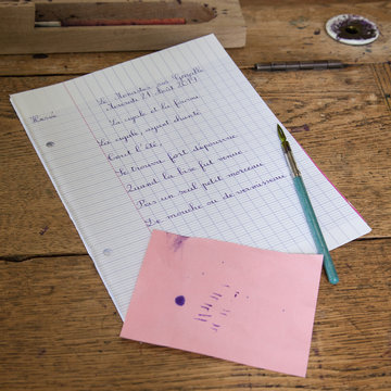 Dict&eacute;e : sur un vieux bureau en bois un porte-plume, un buvard et une page de dict&eacute;e d'une fable de la Fontaine