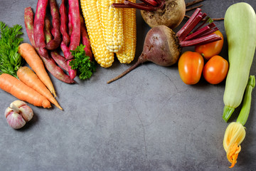 Assorted fresh vegetables on a black background. Corn, tomatoes, zucchini, carrot, beetroot, garlic, bean. Food concept. Flat lay, top view. Free space for your text.