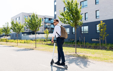 business and people and concept - young businessman with backpack riding electric scooter