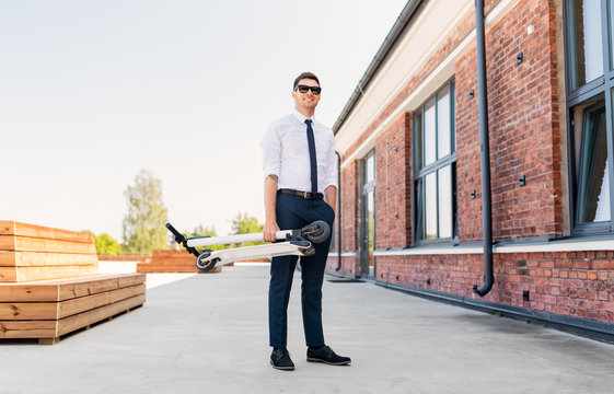 business and people and concept - young businessman with folding scooter on rooftop