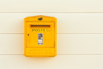 Yellow letterbox of the French postal services on a white wall
