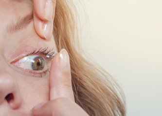 Woman inserts a contact lens into the eye. Close-up, domestic scene. Optics, Vision, Optical...