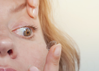 Woman inserts a contact lens into the eye. Close-up, domestic scene. Optics, Vision, Optical...