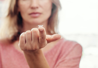 Woman shows contact lens at tip of outstretched finger. Optics, Vision, Optical Instruments.