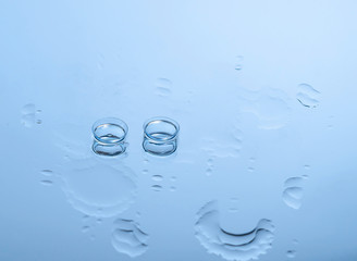 Contact lenses for the eyes on the glass among the drops of water in blue. Optical equipment, good...