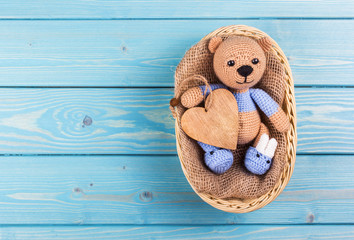 Little crocheted teddy bear on  wooden background.  Teddy bear and heart. Teddy bear copy space
