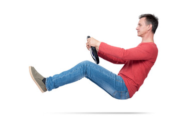 Man in jeans and red t-shirt drives a car with a steering wheel, isolated on white background. Auto...