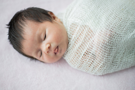 Asian newborn baby sleeping on the bed in living room