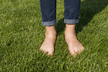 Barefoot little girl standing on grass close-up