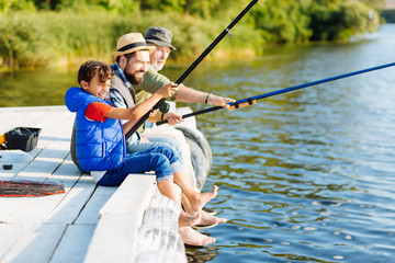 Men of three generations feeling happy while fishing in summer