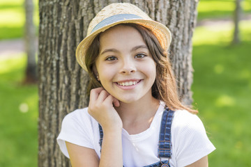 Smiley little girl posing in front of a tree