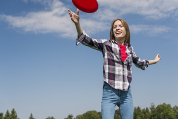 Low angle blonde girl playing with a red frisbee