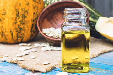 Closeup of a bottle of pumpkin seed essential oil on a napkin with burlap.