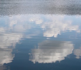 The white clouds reflections off the water surface.