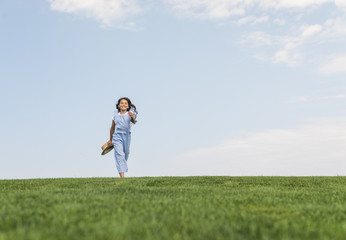 Long shot girl with long hair running on grass