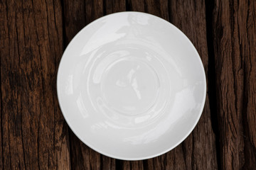 Empty ceramic white plate on wooden background. Top view