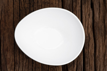 Empty ceramic white bowl on wooden background. Top view