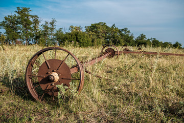 Old rusty wheels of agricultural machinery abandoned in dry grass.