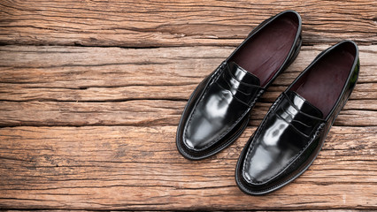 Men fashion of penny loafer black shoes on wooden background. Top view