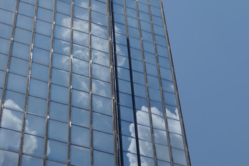 clouds and blue sky reflected on glass building