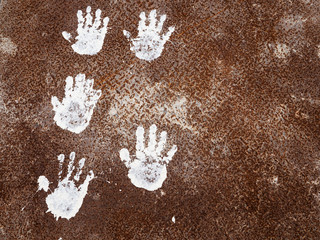 White hand prints on a rusty metal plate background. Top view