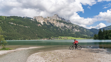 nice and active senior woman, riding her e-mountain bike in the Tannheim valley along side the...
