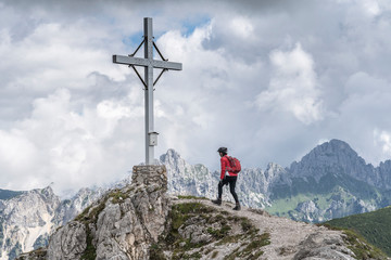 nice and active senior woman approaching the summit of Litnis Schrofen during a bike and hike adventure in the Tannheim Valley, Tirol Austria