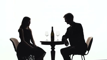 Silhouettes of a girl and a guy sitting at a table on a white background
