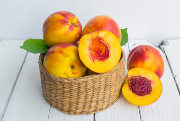 Delicious and juicy peach (nectarina) in basket  on white wooden table