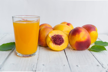 Delicious and juicy peach (nectarina) with glass of juice on white wooden table