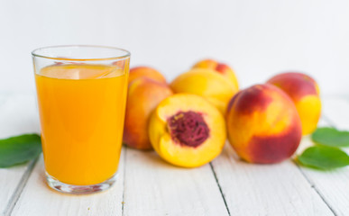 Delicious and juicy peach (nectarina) with glass of juice on white wooden table