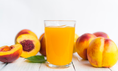 Delicious and juicy peach (nectarina) with glass of juice on white wooden table