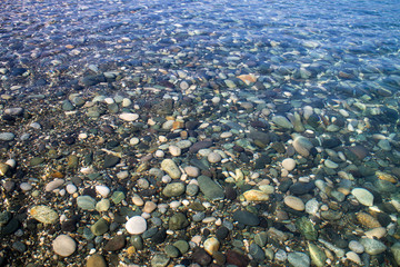 Sea stones in sea water. Pebbles under water. The view from the top. Nautical background. Clean sea water. Transparent sea.