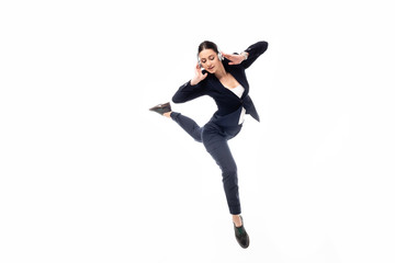 young, pretty businesswoman listening music in headphones and dancing isolated on white