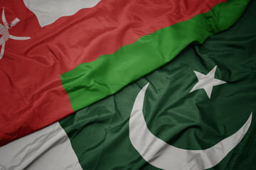 waving colorful flag of pakistan and national flag of oman.