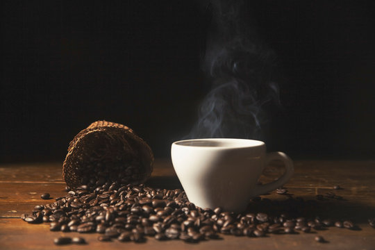 Hot black coffee in cup with coffee bean .