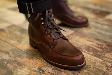 Brown leather men’s boots on legs closeup view