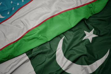 waving colorful flag of pakistan and national flag of uzbekistan.