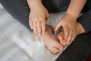 Close up image of toddler's feet and hands on the bed