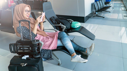 Muslim Young woman With headscarf sitting and use smartphone on airport waiting room. Beautiful young woman traveler walking waiting or looking for her flight