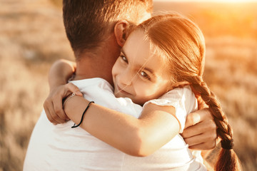 Daughter hugging anonymous father in countryside