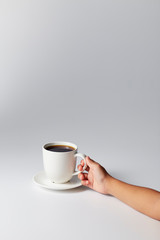 Hand holding a white cup of coffee
