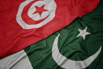 waving colorful flag of pakistan and national flag of tunisia.