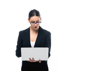 attentive businesswoman in formal wear and glasses using laptop isolated on white