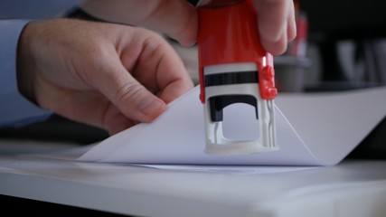 Businessman Hand Stamping Papers and Documents Using a Rubber Stamp