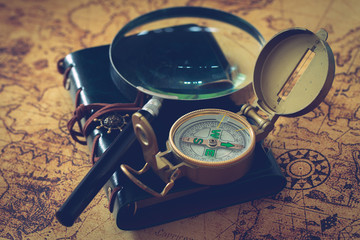 old map with compass, notebook and magnifying glass.  The concept of searching for interesting places or treasures around the world.